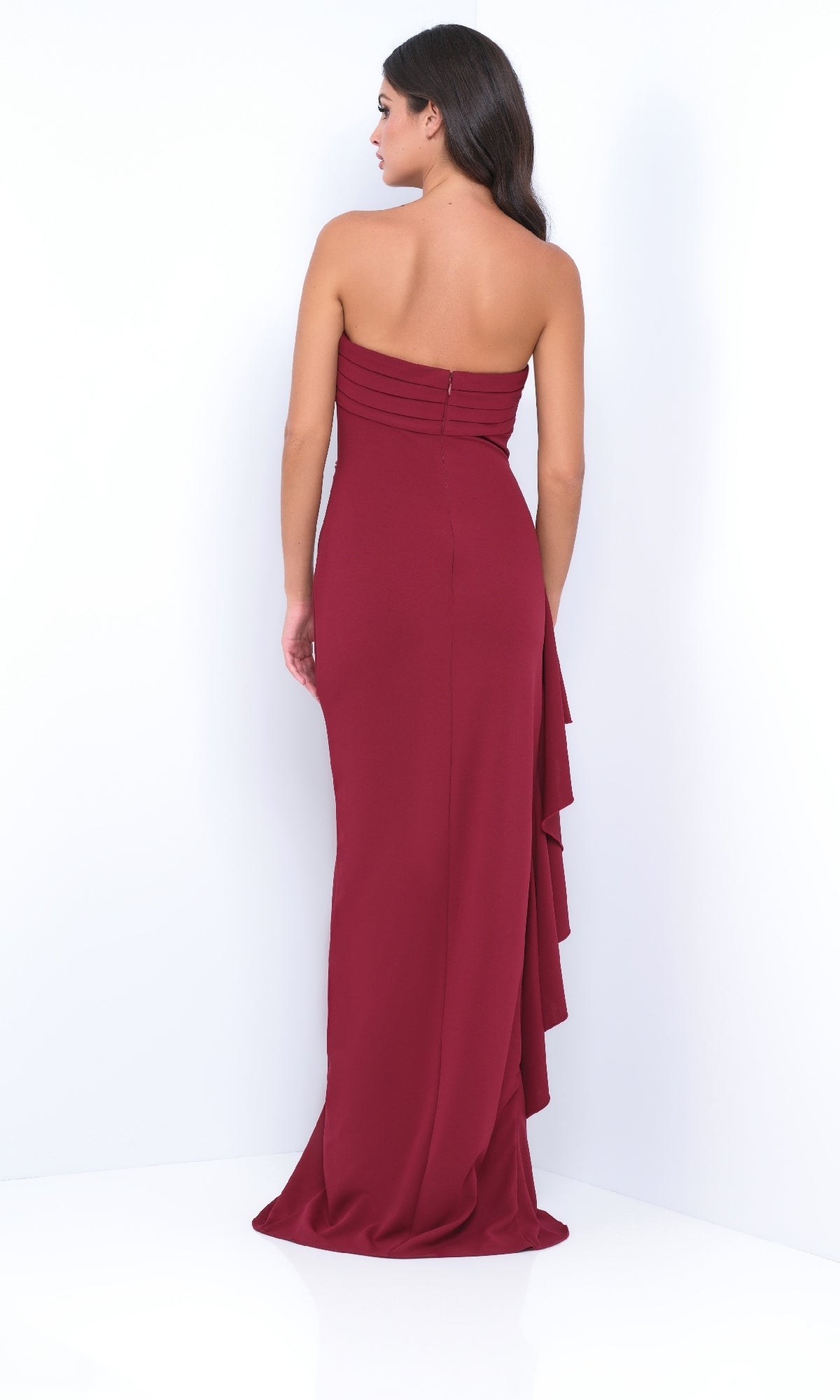 Woman in the Strapless Long Ruffle Prom Dress: Velvi Marie—floor-length maroon gown with back ruffle detail—posing against a white background.